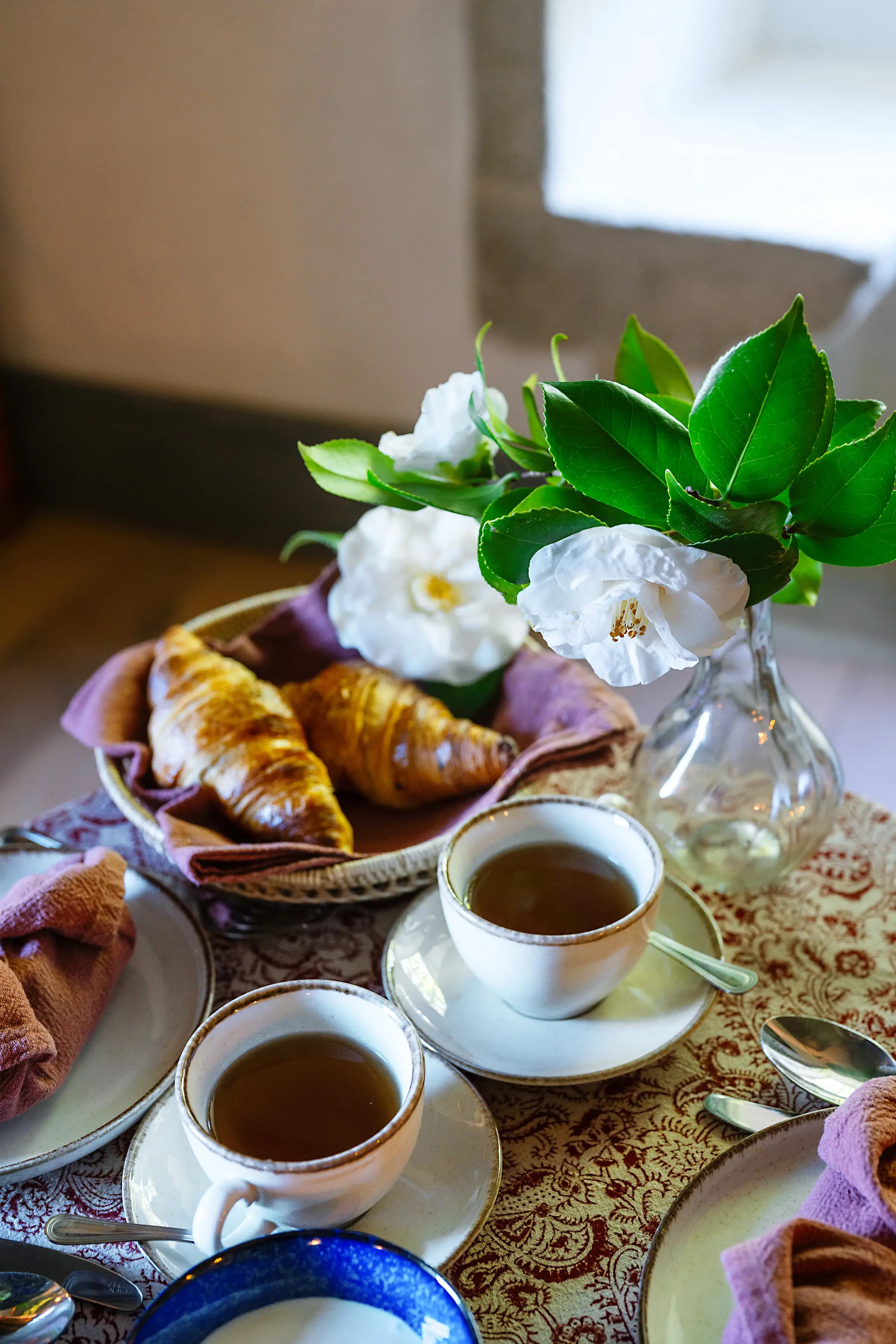 A breakfast tray of croissants, coffee and gardenias