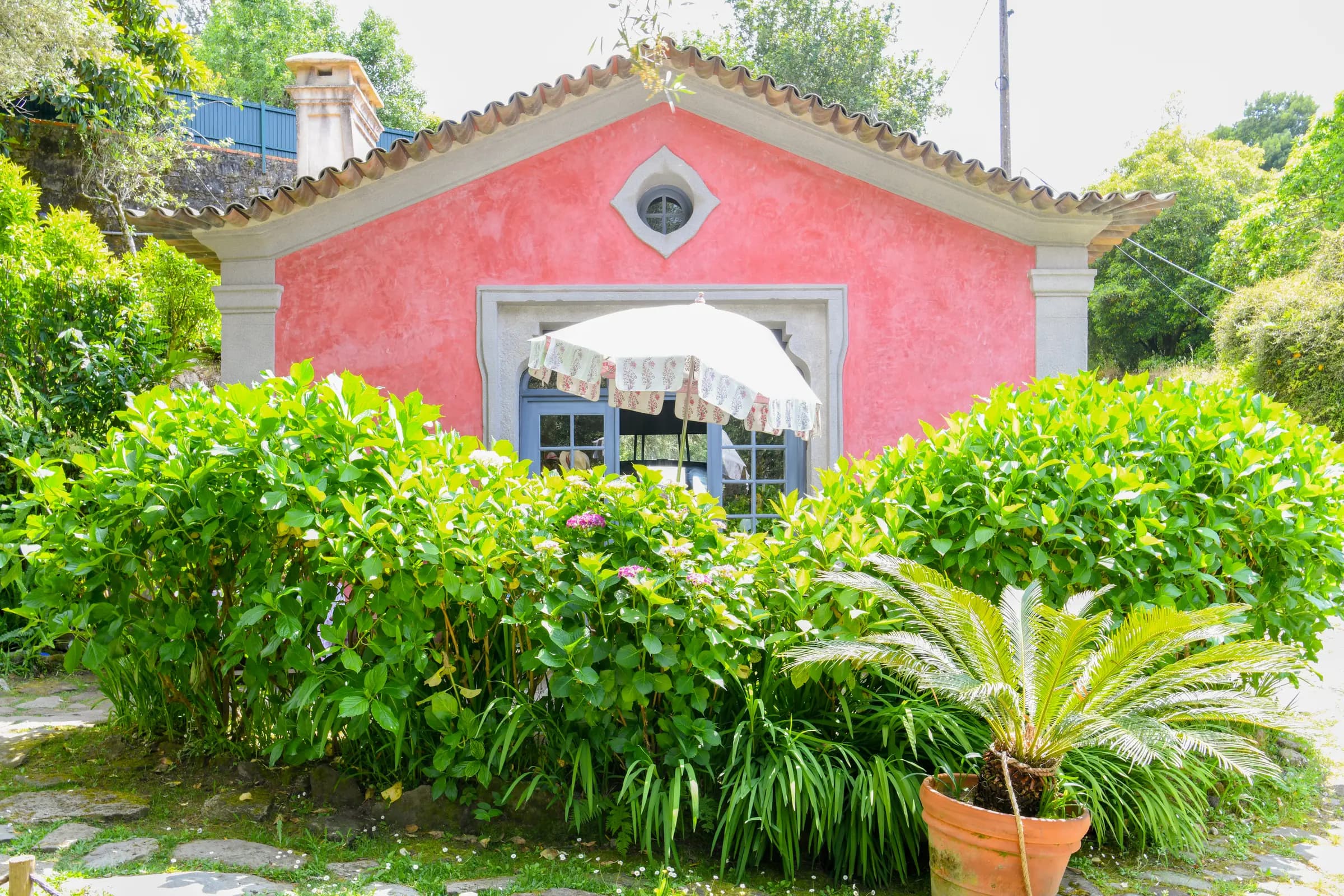 The rose-pink Café de Cabanas house among hydrangeas