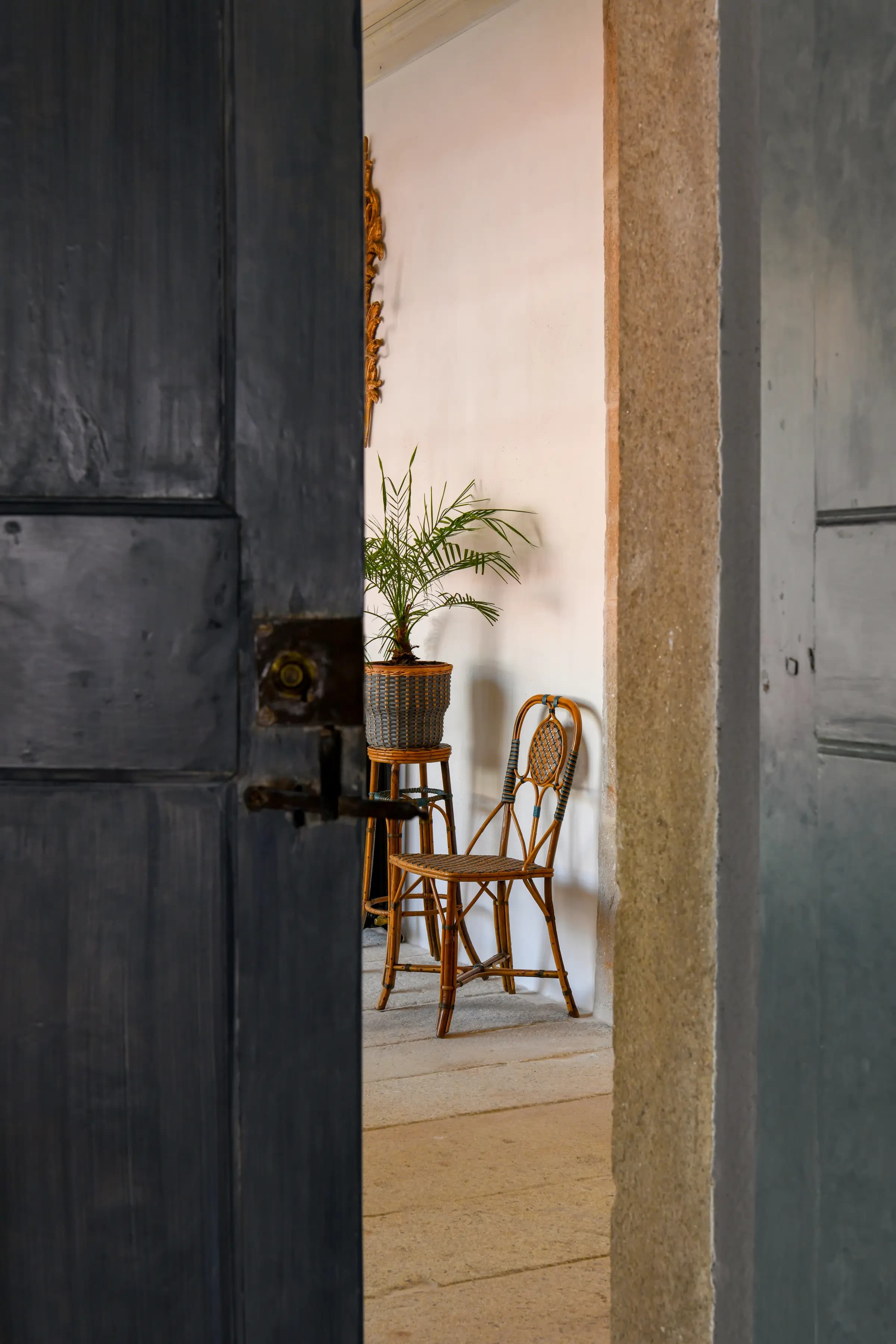 A heavy Convento door ajar, opening onto a quiet room