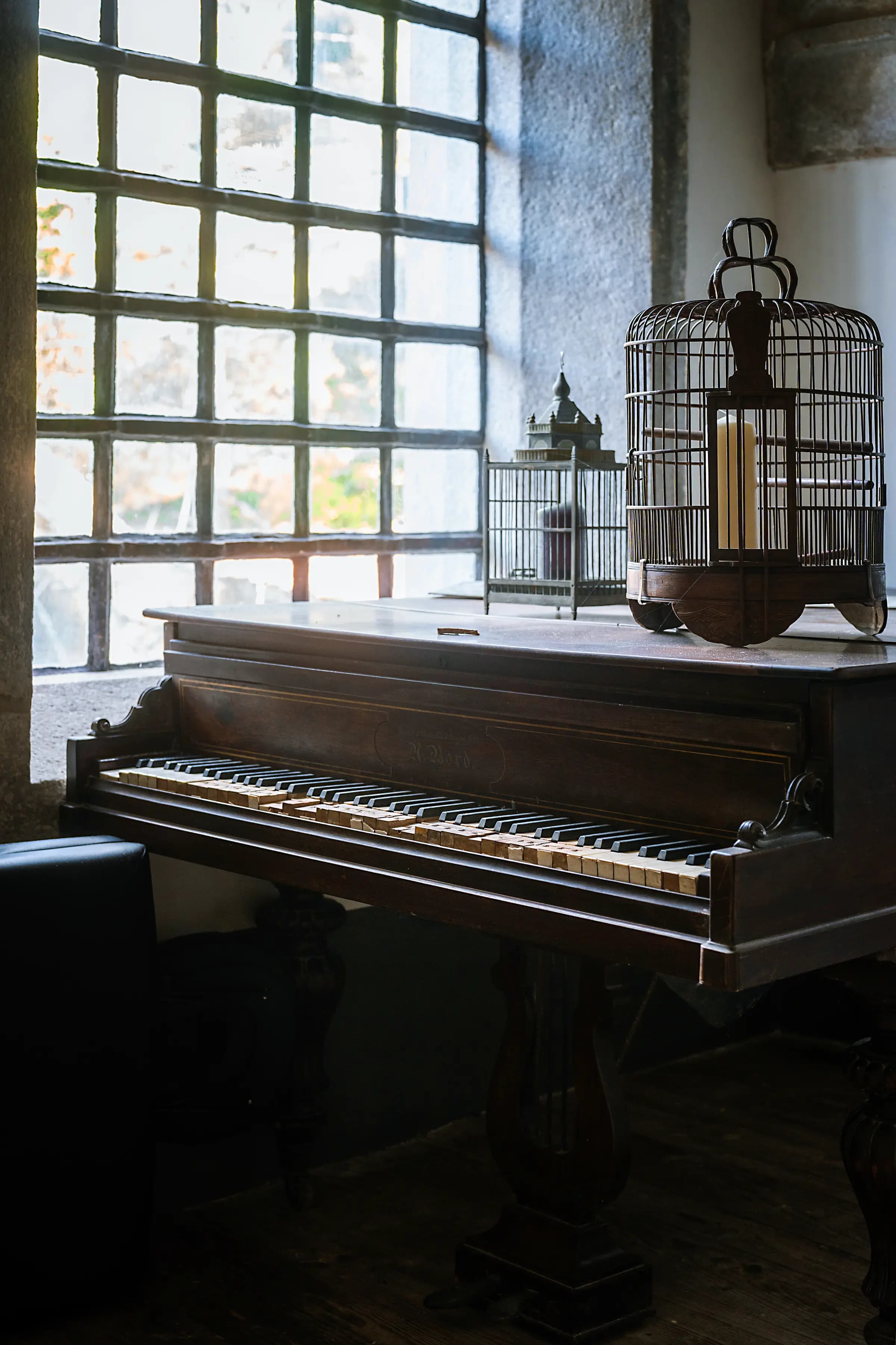 A grand piano beneath the leaded window of the Convento
