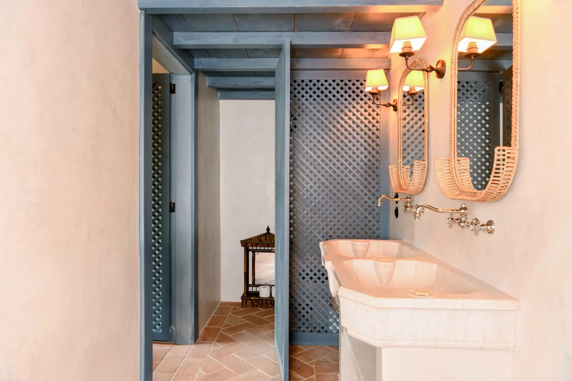 A stone basin under oval mirrors, framed by blue latticework