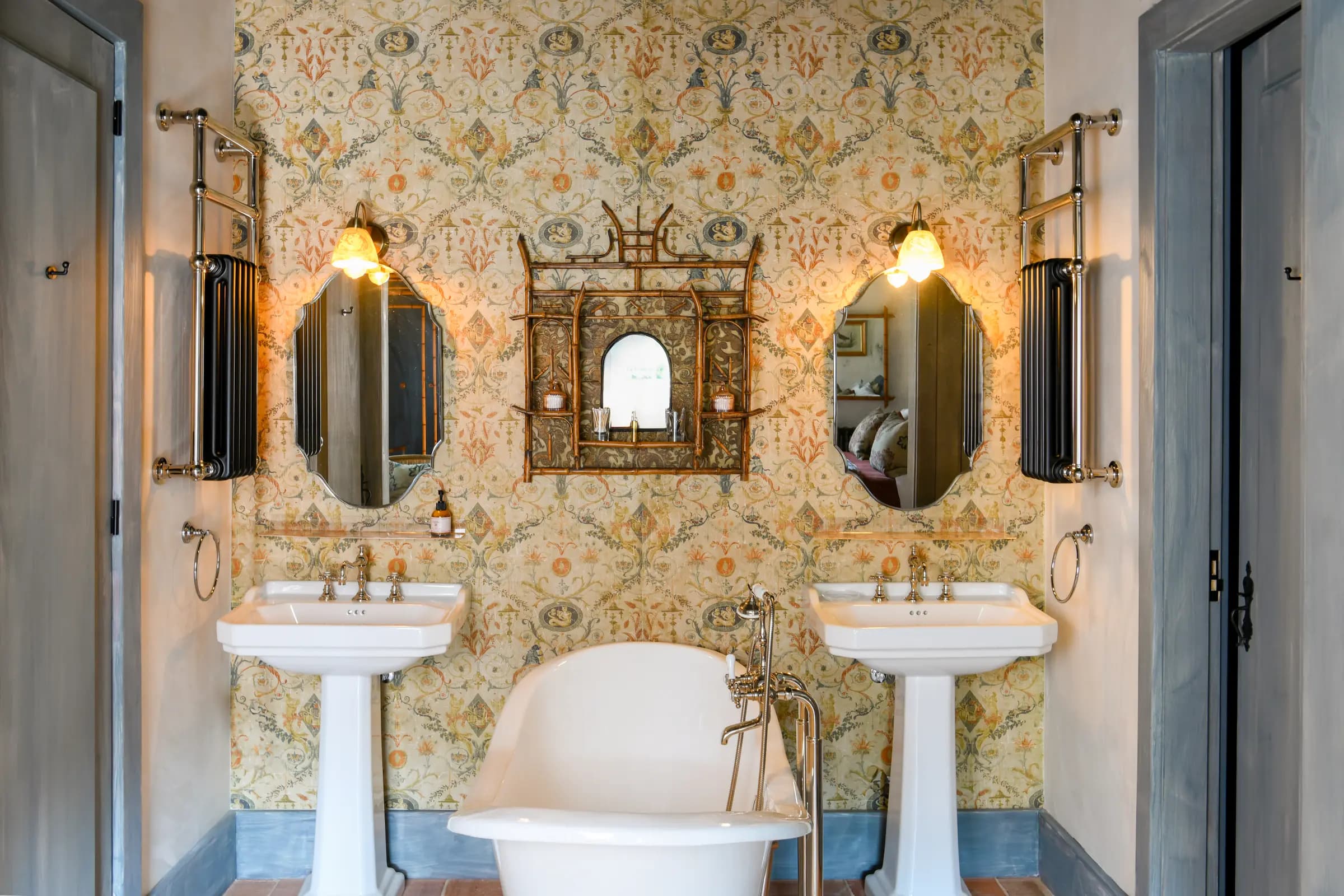 Twin pedestal basins beneath ornate mirrors and tapestry-papered walls
